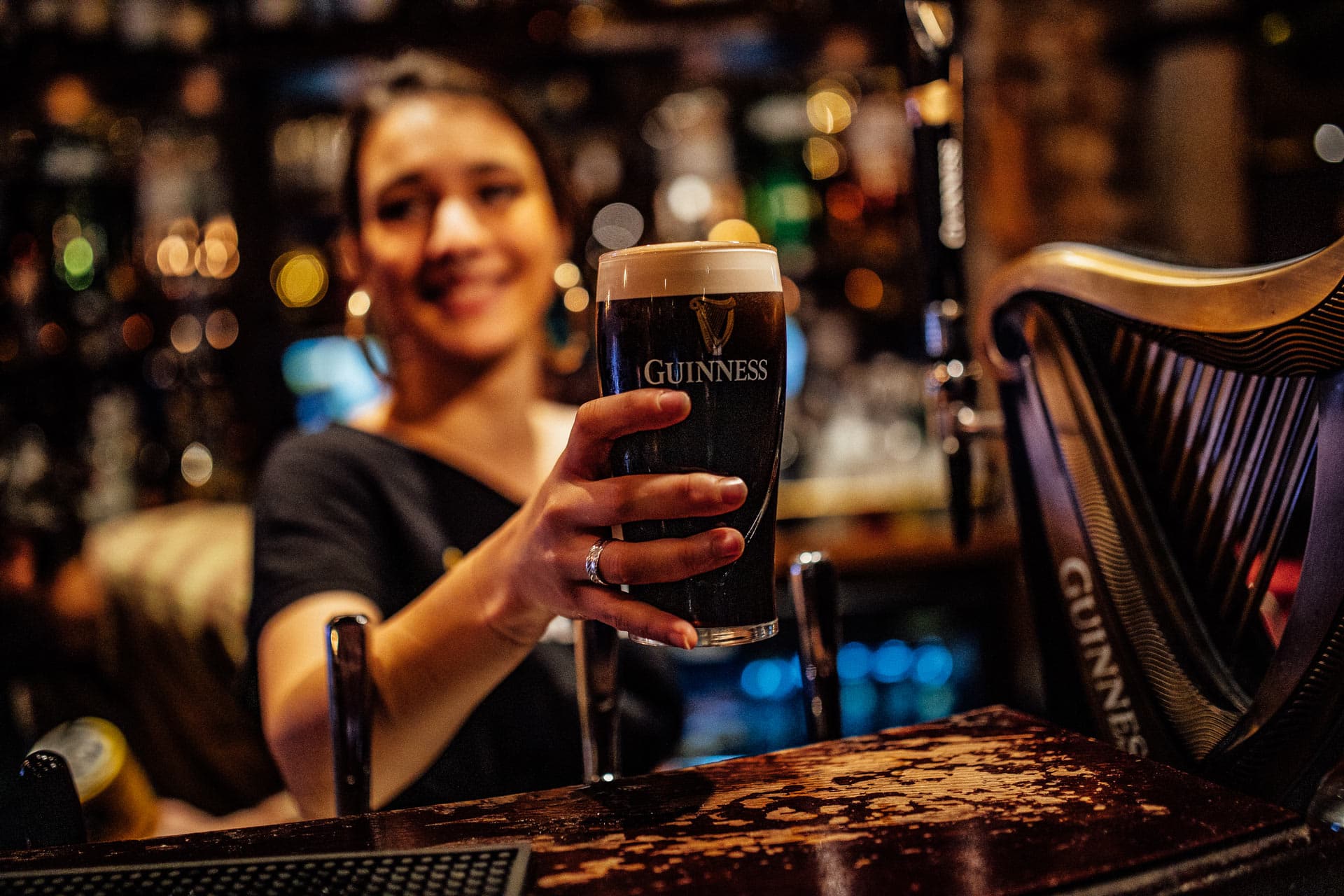 woman behind a bar serving a guinness